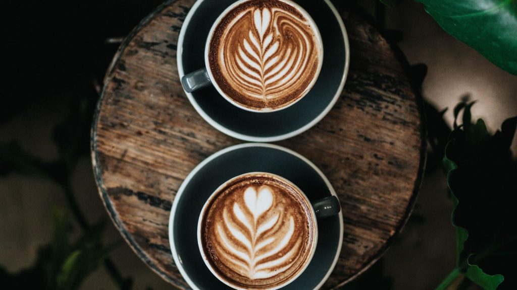 Zwei wunderschön gestaltete Milchkaffees, verziert mit kunstvollen Latte-Art-Motiven.
